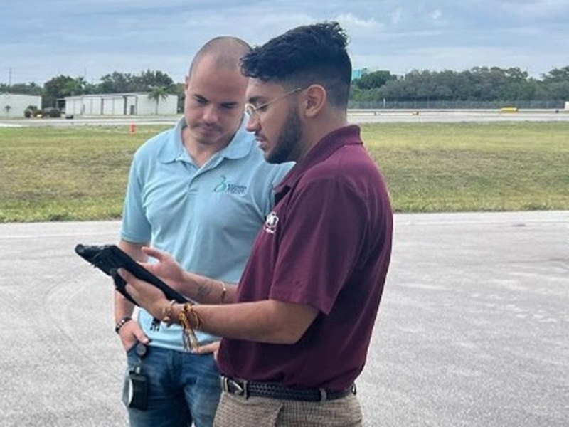 Two Simplify i3® team members reviewing a tablet together during a field training session at an airfield